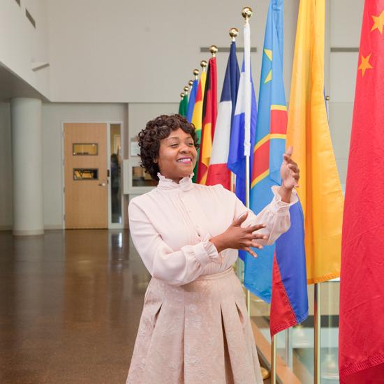 sign language interpreter with many different nation's flags behind her